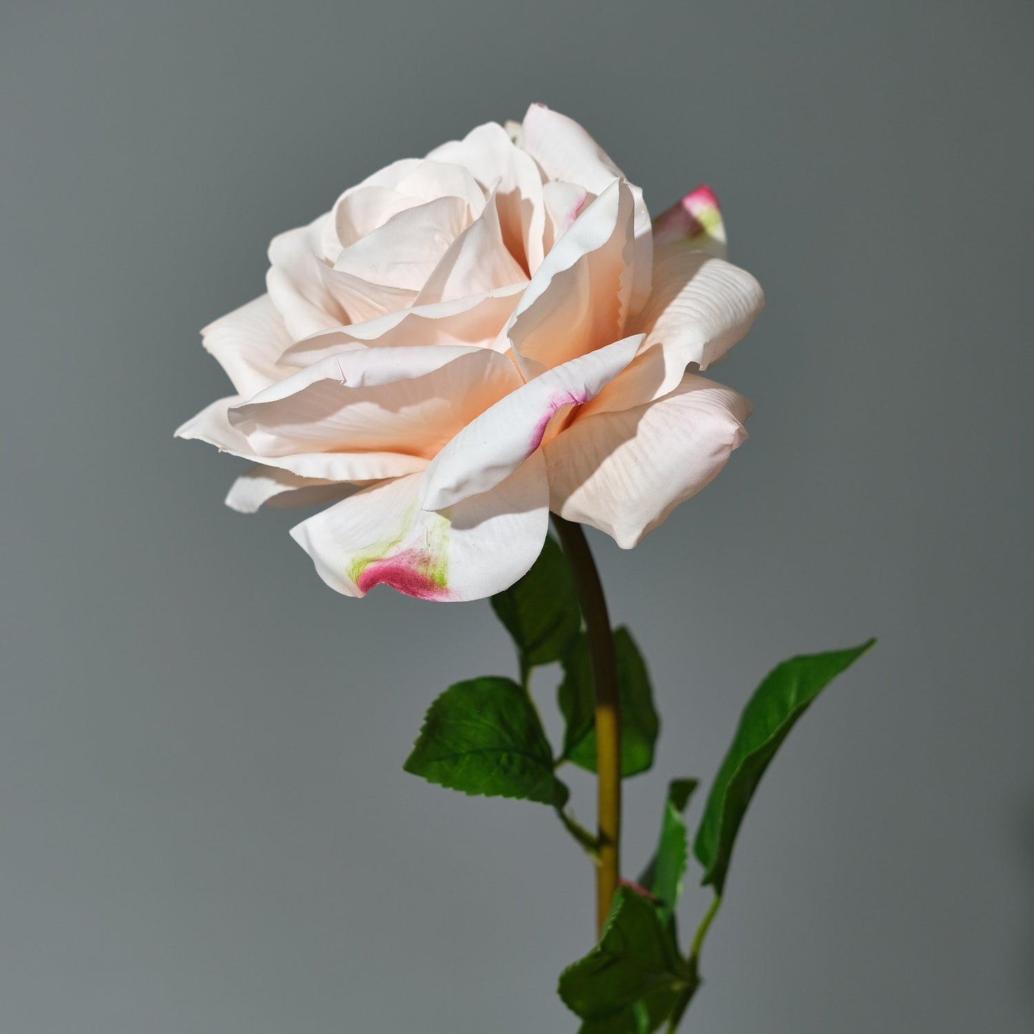 Stor konstgjord bukett Rosy Riviera med exklusiva rosor i rosa och aprikos nyanser, arrangerad med gröna blad i en stilren vas. Närbild