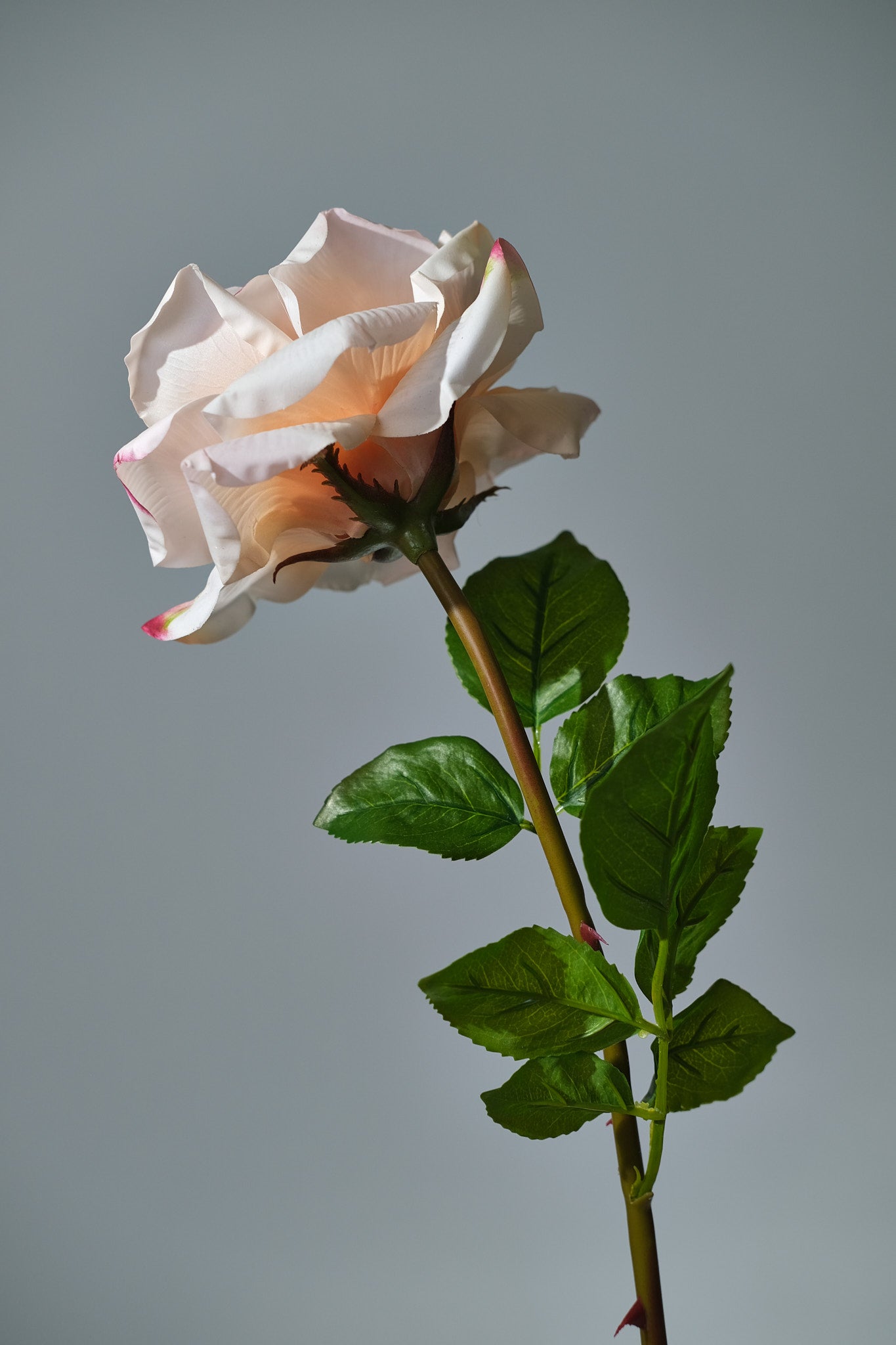 Stor konstgjord bukett Rosy Riviera med exklusiva rosor i rosa och aprikos nyanser, arrangerad med gröna blad i en stilren vas. Detaljbild på ros