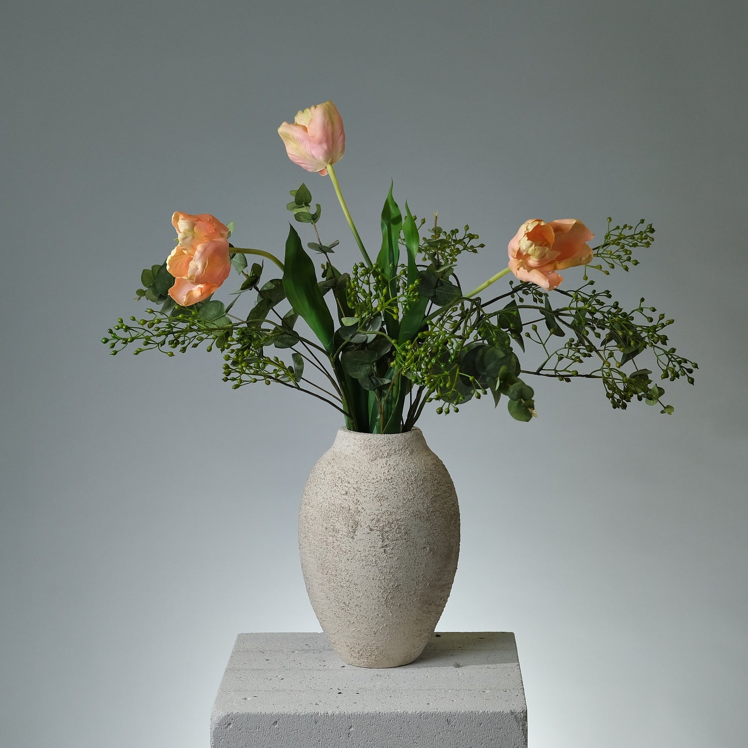 Bukett i konstblommor med rosa/krämfärgade tulpaner, grön eukalyptus och dekorativa gröna bär – i en naturlig och stilren komposition - FLORISSMA