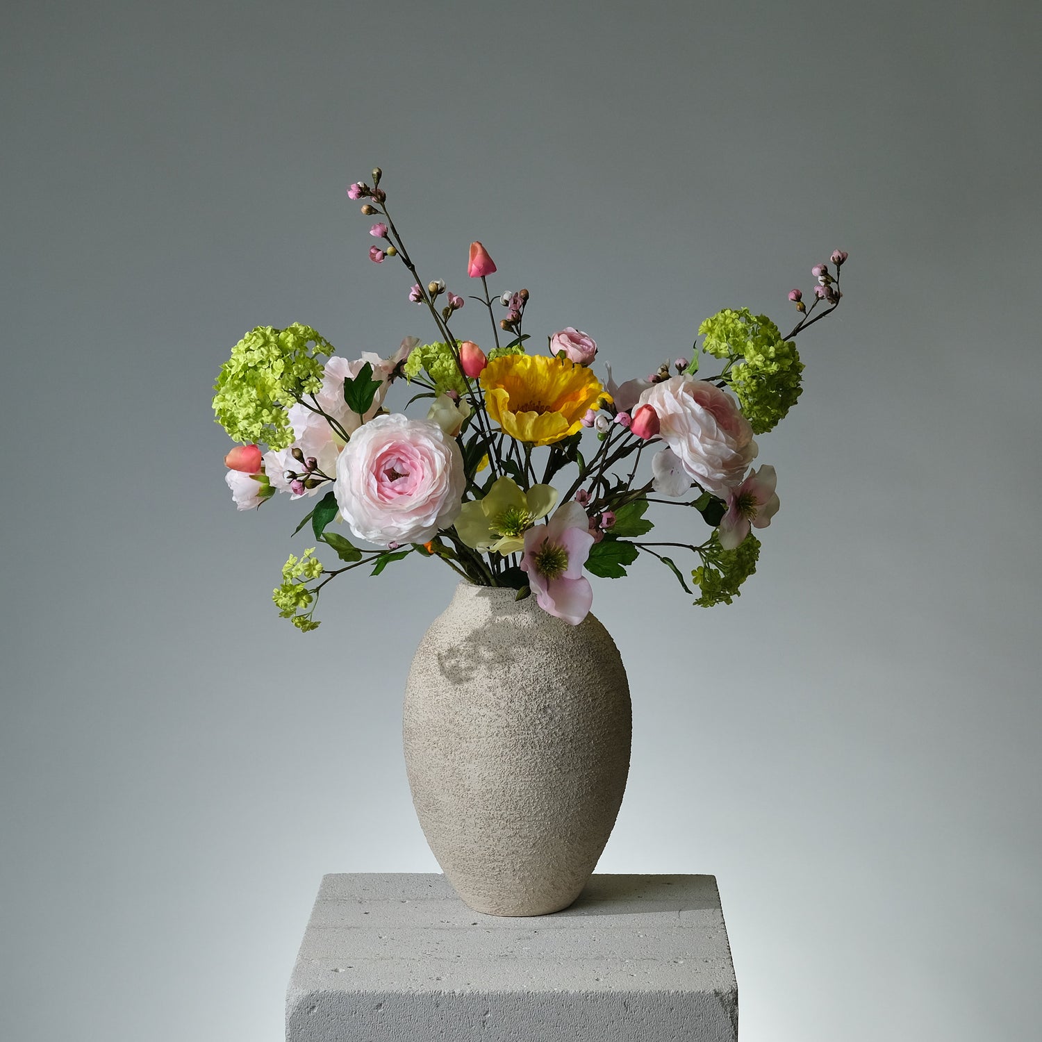 Bukett i konstblommor med rosa pion, gul vallmo, persikofärgad ranunkel, gröna snowballs och julrosor i rosa och persikogrönt – livlig och elegant blomkomposition - FLORISSMA