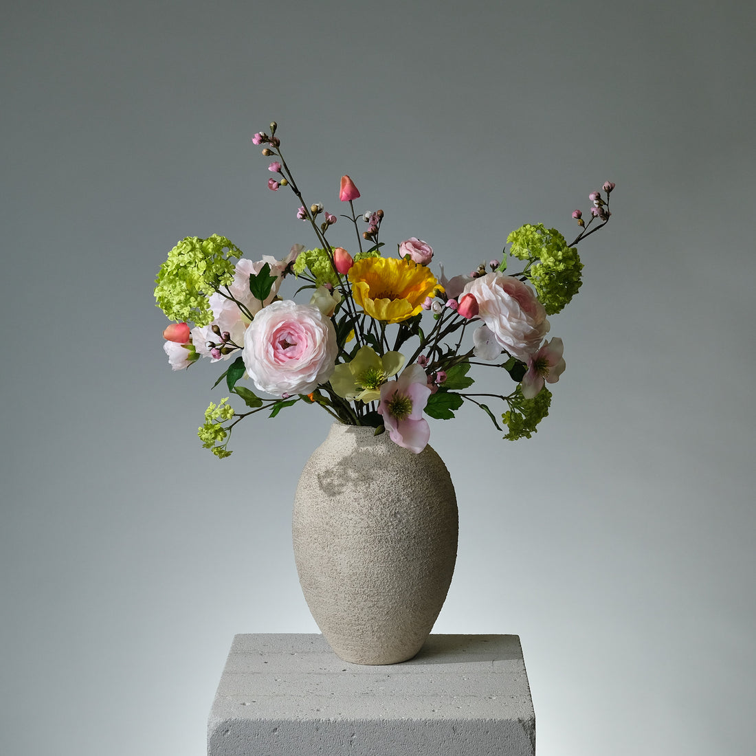 Bukett i konstblommor med rosa pion, gul vallmo, persikofärgad ranunkel, gröna snowballs och julrosor i rosa och persikogrönt – livlig och elegant blomkomposition - FLORISSMA