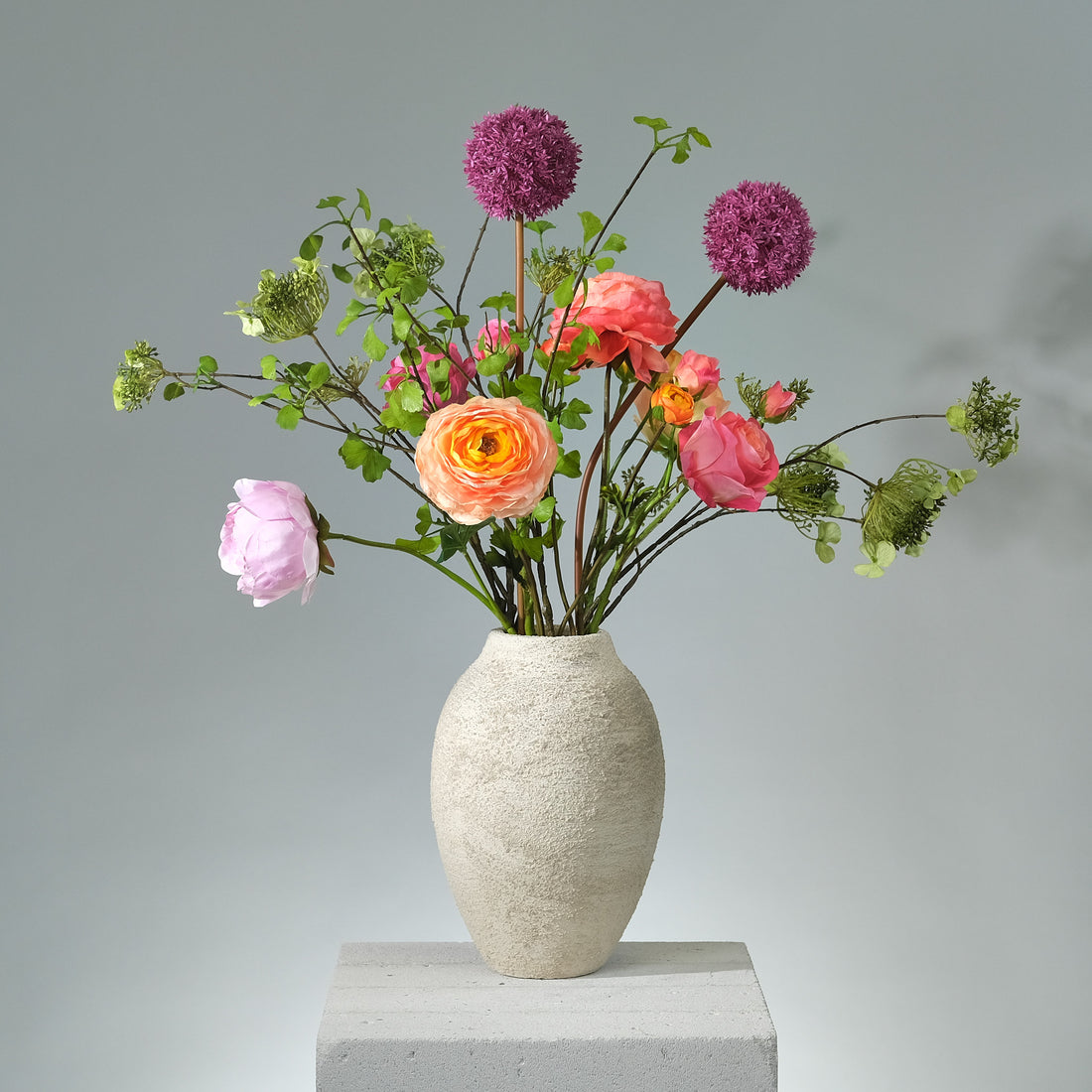Lush Bloomscape konstblomsbukett med starka rosa, orangea och gröna toner – livfullt arrangerad med silkesblommor och blad. FLORISSMA
